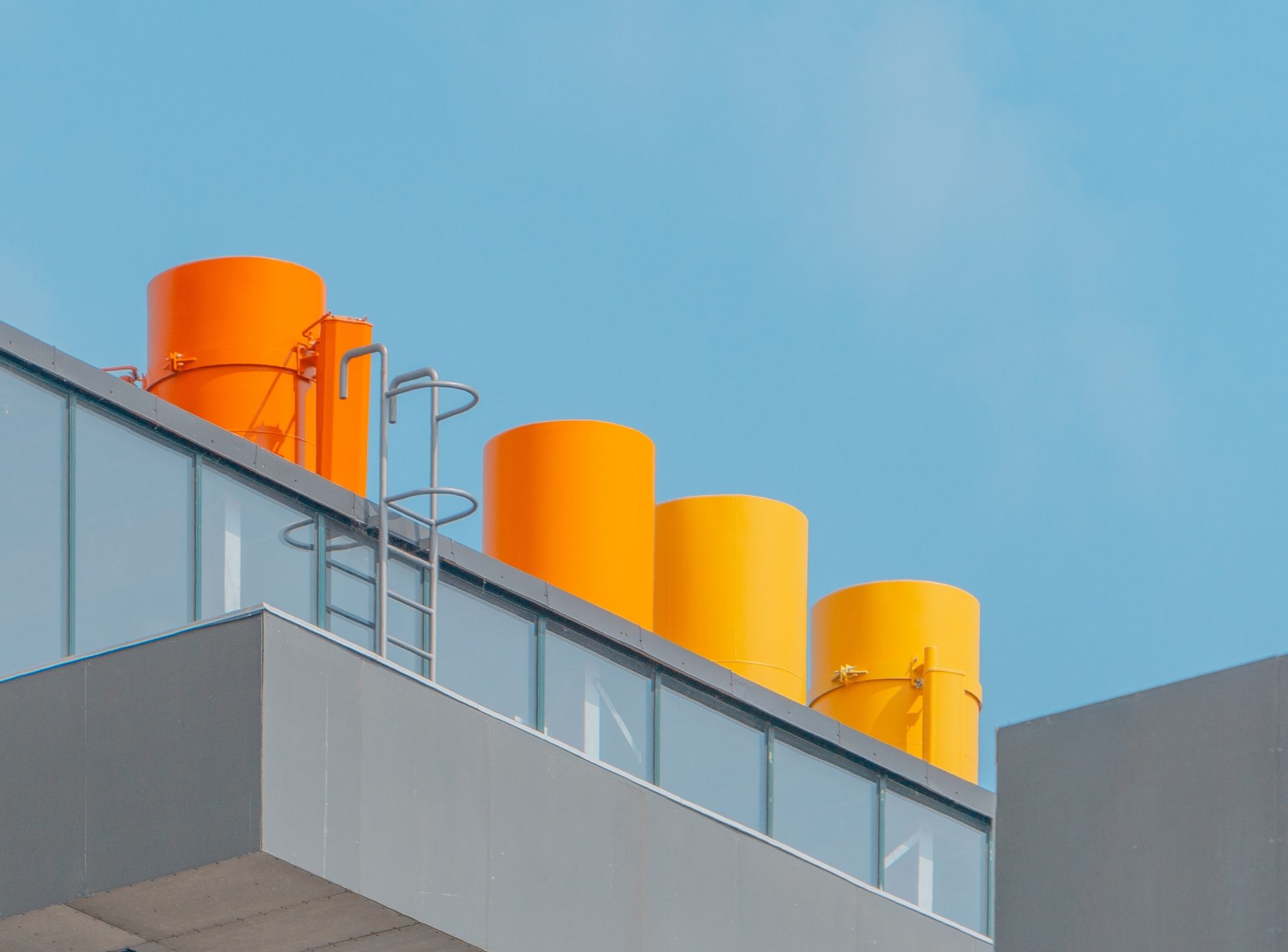 vertical-shot-glass-building-with-orange-chimneys-blue-sky
